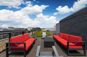 a roof deck with red couches and tables on a sunny day at The Shay, Washington, DC 20001